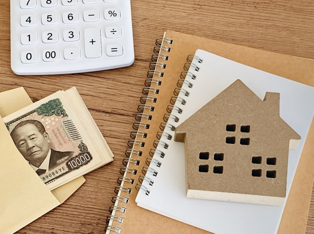 家の模型と電卓と現金